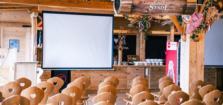 Aufgebaute SItzreihen vor einer Leinwand im Eventstadl