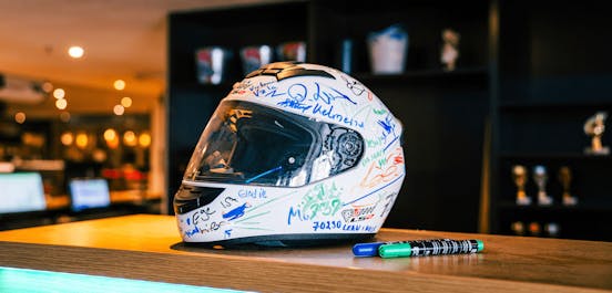 Ein Helm mit vielen verschiedenen Unterschriften stehst auf dem Tresen im Empfangsbereich.