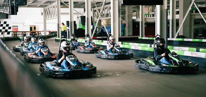 Eine Gruppe von Kartfahrern steht aufgereiht in der Startaufstellung vor dem Ampelstart