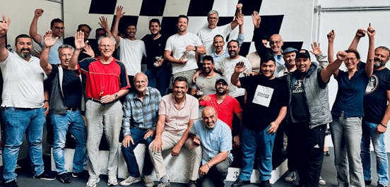 Eine große Gruppe an Kartfahrern steht auf und neben dem Siegerpodest und jubelt