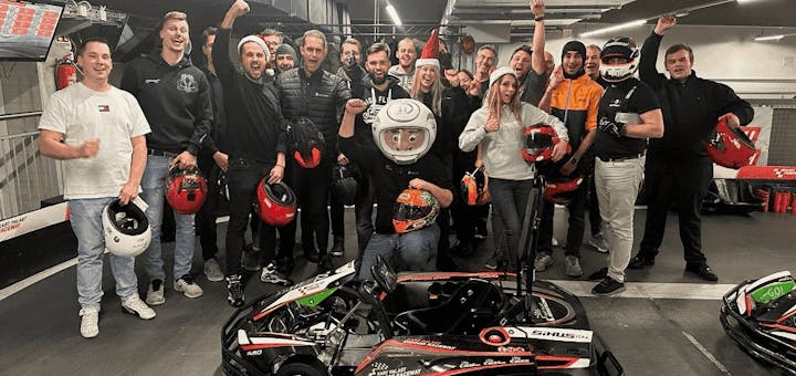 Eine Gruppe von jungen Leuten steht in der Boxengasse und freut sich auf das Rennen