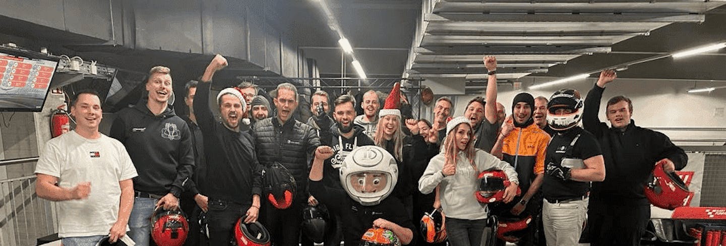 Eine Gruppe von Kartfahrern steht vor Renngebinn in der Boxengasse