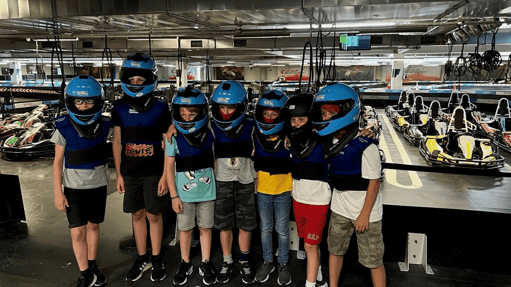 Eine Gruppe von Kindern mit Helmen steht vor der Rennstrecke