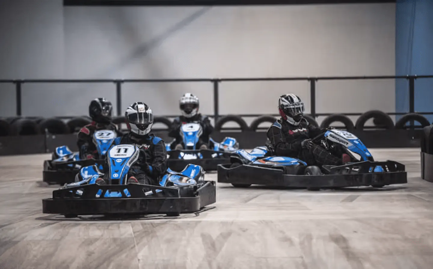 Drivers racing electric go-karts on a TeamSport indoor track