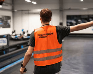 Member of TeamSport staff directing karts on track 
