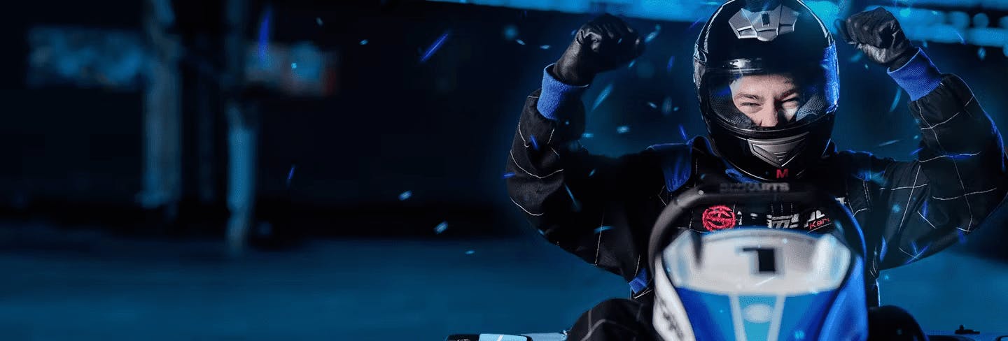 Man sitting in a Go Kart smiling with arms in the air