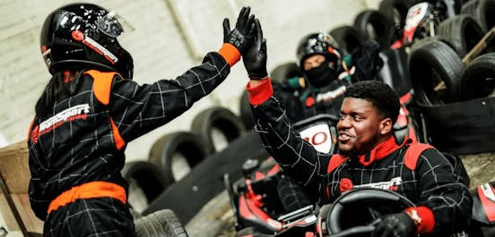 two karters high-fiving as one sits in kart