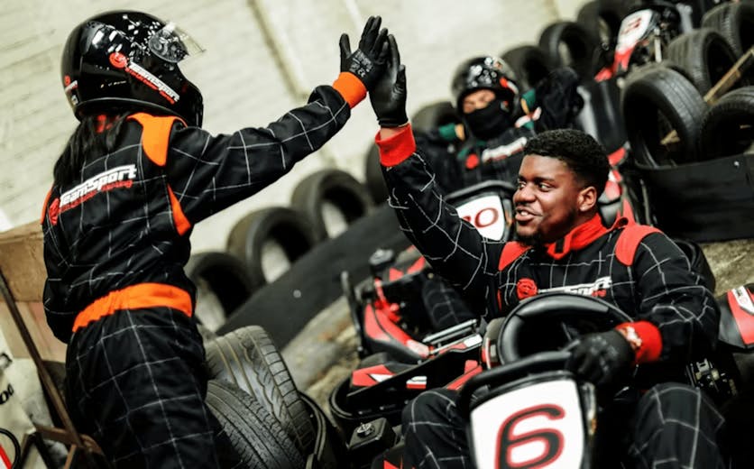 two karters high-fiving as one sits in kart