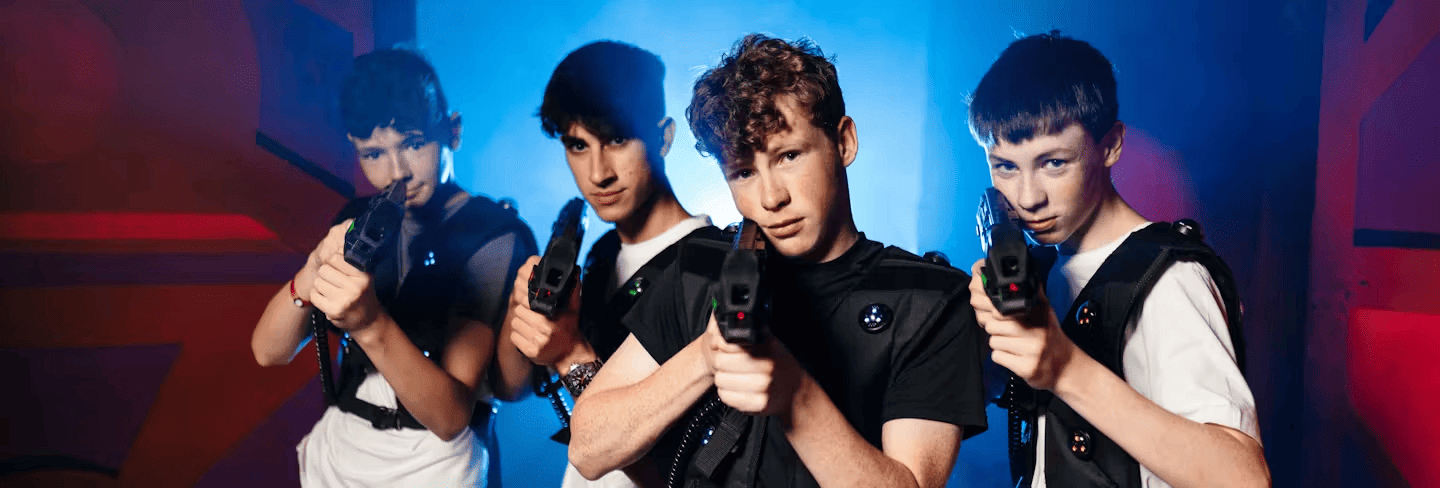 Four boys aiming their laser combat weapons at camera