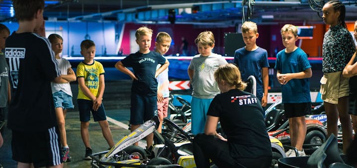 Kinder stehen um ein Kart und erhalten eine ausführliche Sicherheitseinweisung