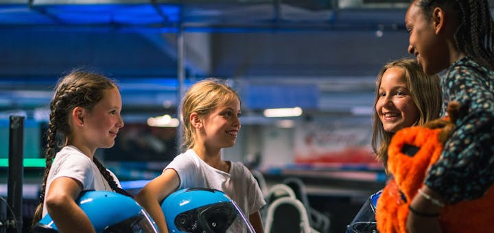 Vier Mädchen mit Helmen in der Hand stehen an der Rennstrecke und haben Spaß!