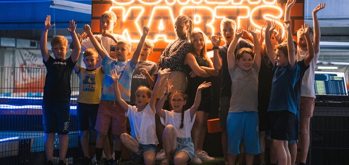 Eine Gruppe von Kindern und Jugendlichen steht auf dem Combat Karts Podest und jubelt