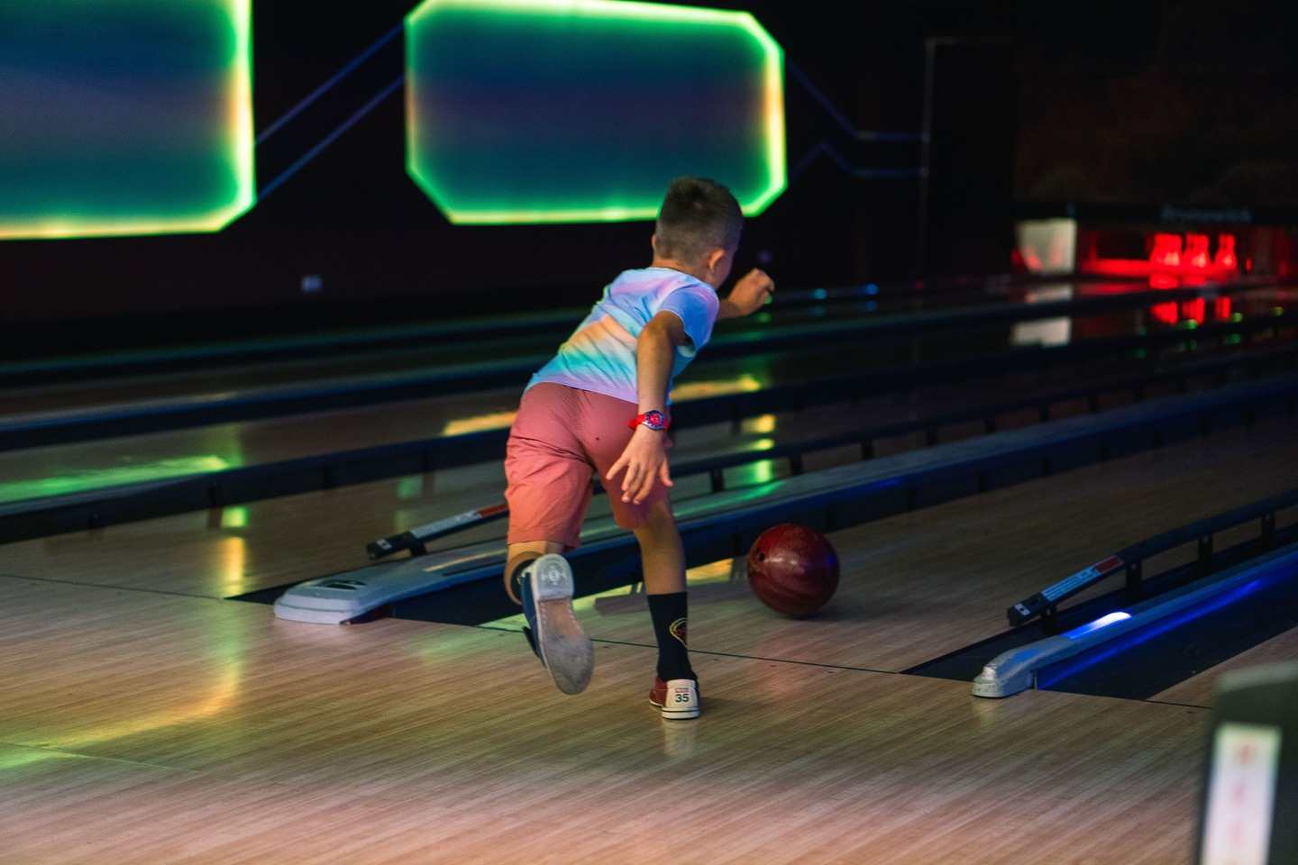 Eine Junge spielt Bowling und wirft gerade die Kugel