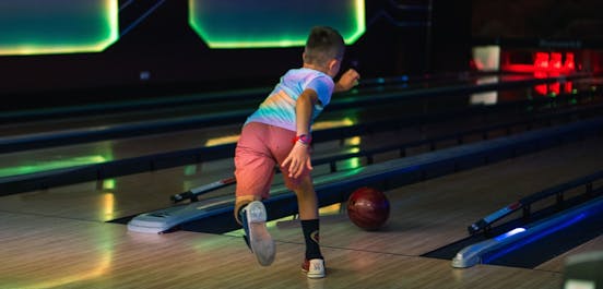 Eine Junge spielt Bowling und wirft gerade die Kugel