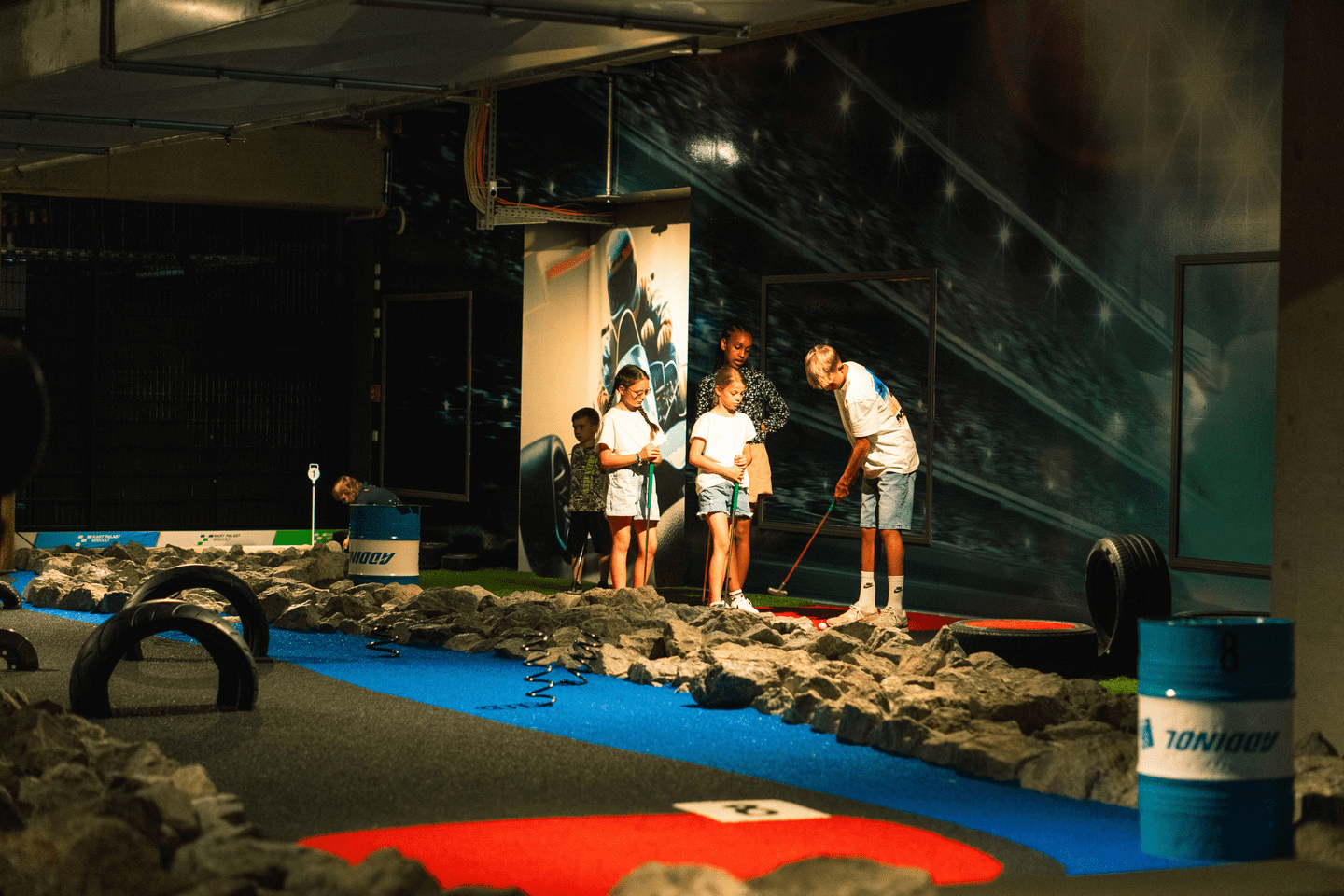 5 Kinder spielen Minigolf auf dem 9-Loch Platz im Motorsport Look