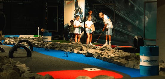 5 Kinder spielen Minigolf auf dem 9-Loch Platz im Motorsport Look