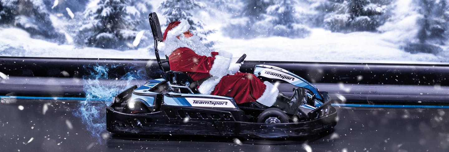 Santa Clauss sitzt in einem TeamSport E-Kart und fährt in weihnachtlicher Stimmung über die Rennstrecke