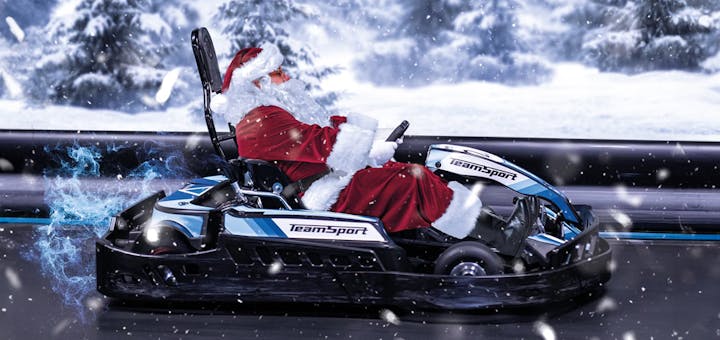 Santa Clauss sitzt in einem TeamSport E-Kart und fährt in weihnachtlicher Stimmung über die Rennstrecke