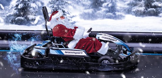 Santa Clauss sitzt in einem TeamSport E-Kart und fährt in weihnachtlicher Stimmung über die Rennstrecke