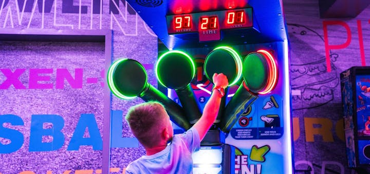 Ein Junge spielt an einem Automaten im Arcade Bereich