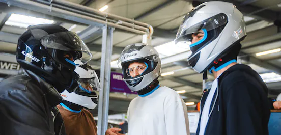 Männer mit Helmen vor dem Rennen in der Boxengasse