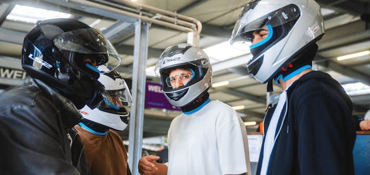 Männer mit Helmen vor dem Rennen in der Boxengasse