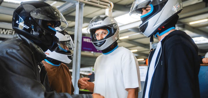 Männer mit Helmen vor dem Rennen in der Boxengasse
