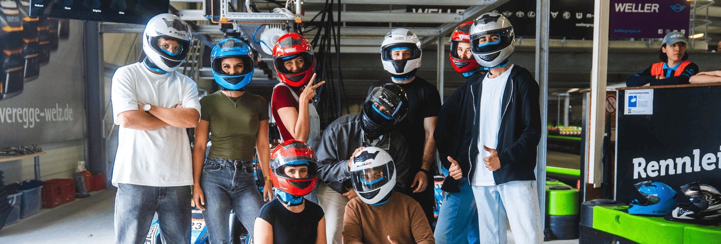 Eine große Gruppe von Teilnehmern mit Helmen vor dem Rennen in der Boxengasse