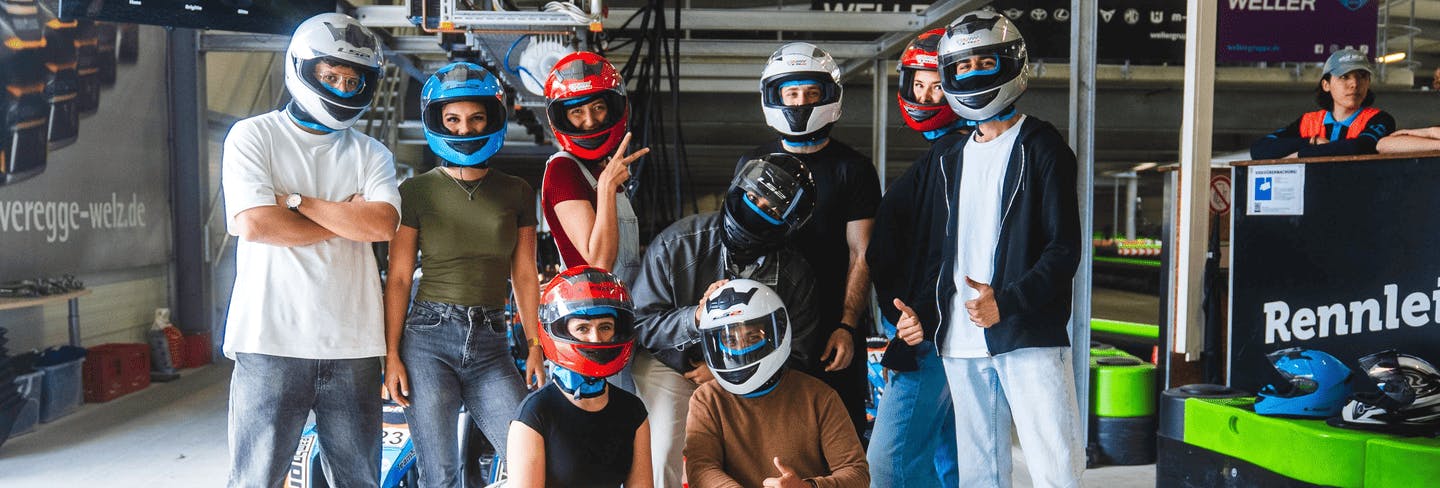 Eine große Gruppe von Teilnehmern mit Helmen vor dem Rennen in der Boxengasse