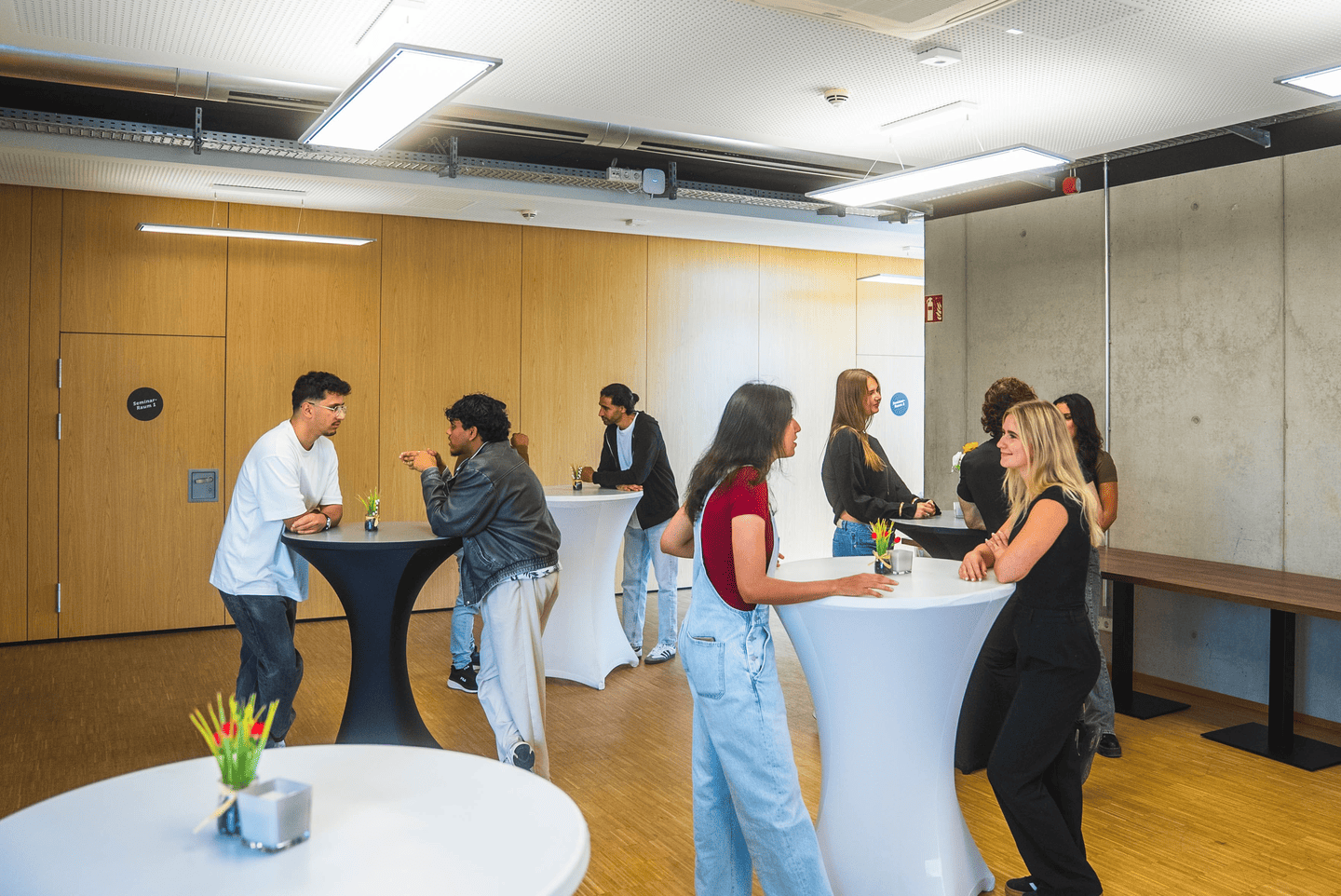 Eine Gruppe von Menschen steht an Hochtischen und unterhält sich!