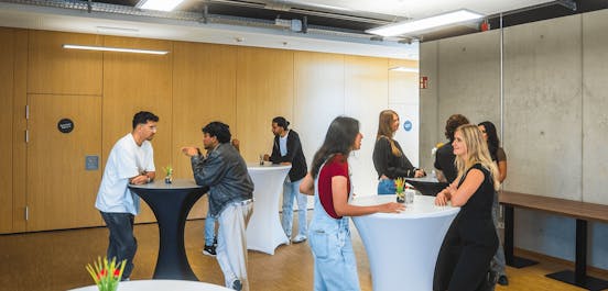 Eine Gruppe von Menschen steht an Hochtischen und unterhält sich!