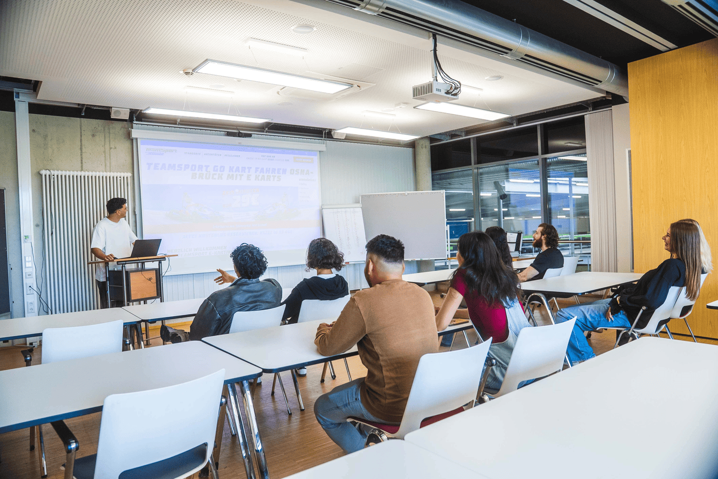 Eine Gruppe schaut einer Präsentation im Meeting Raum zu.
