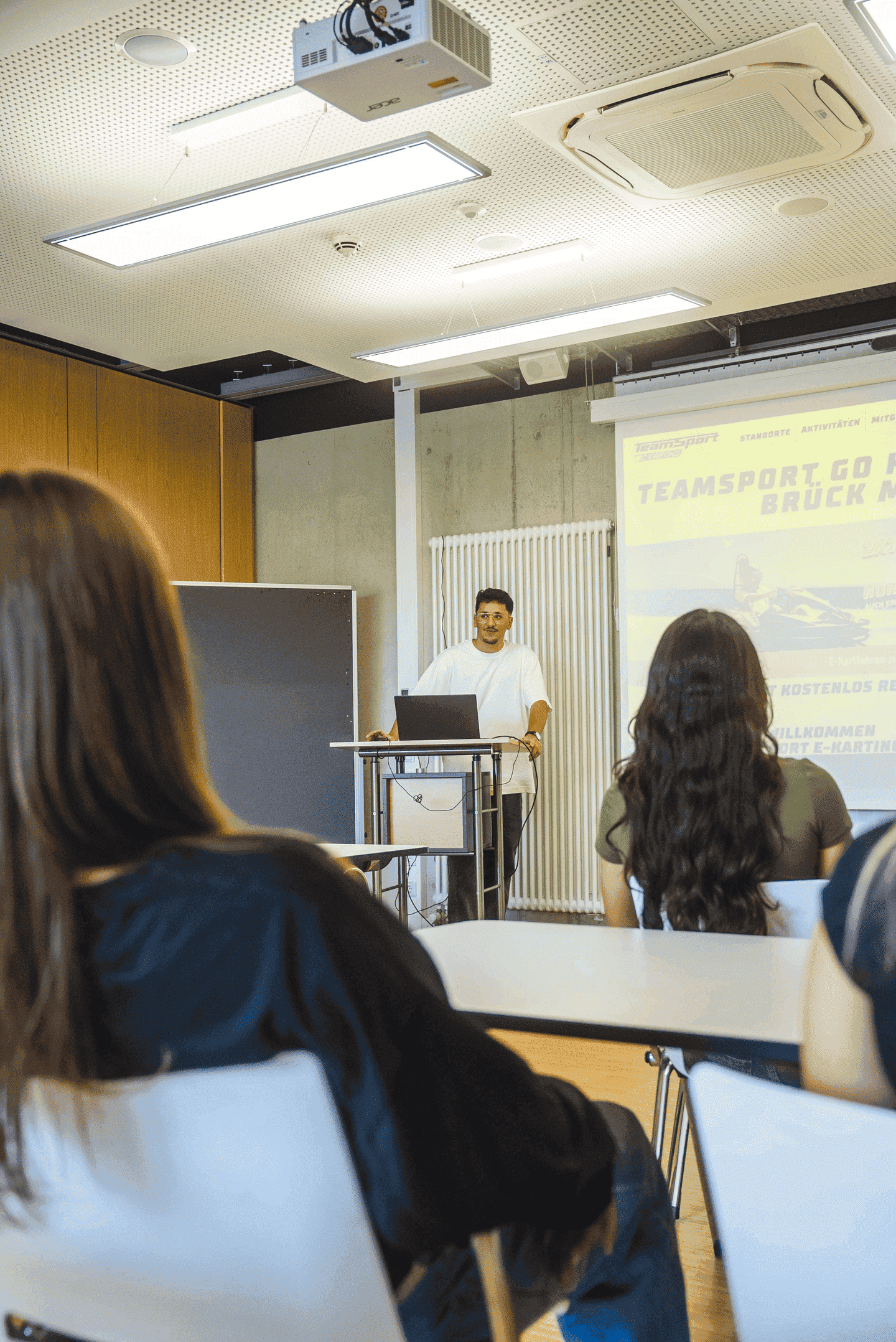 Eine Gruppe schaut einer Präsentation im Meeting Raum zu.