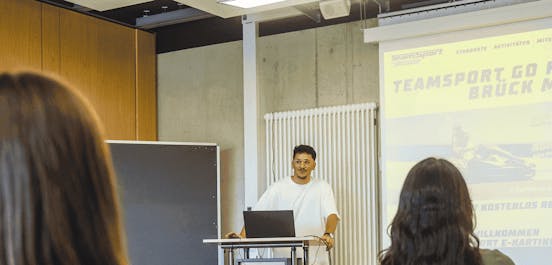 Eine Gruppe schaut einer Präsentation im Meeting Raum zu.