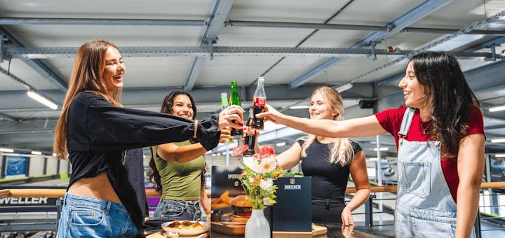 Eine Gruppe von Frauen steht auf der Aussichtsplattform an einem Tisch und stößt an.