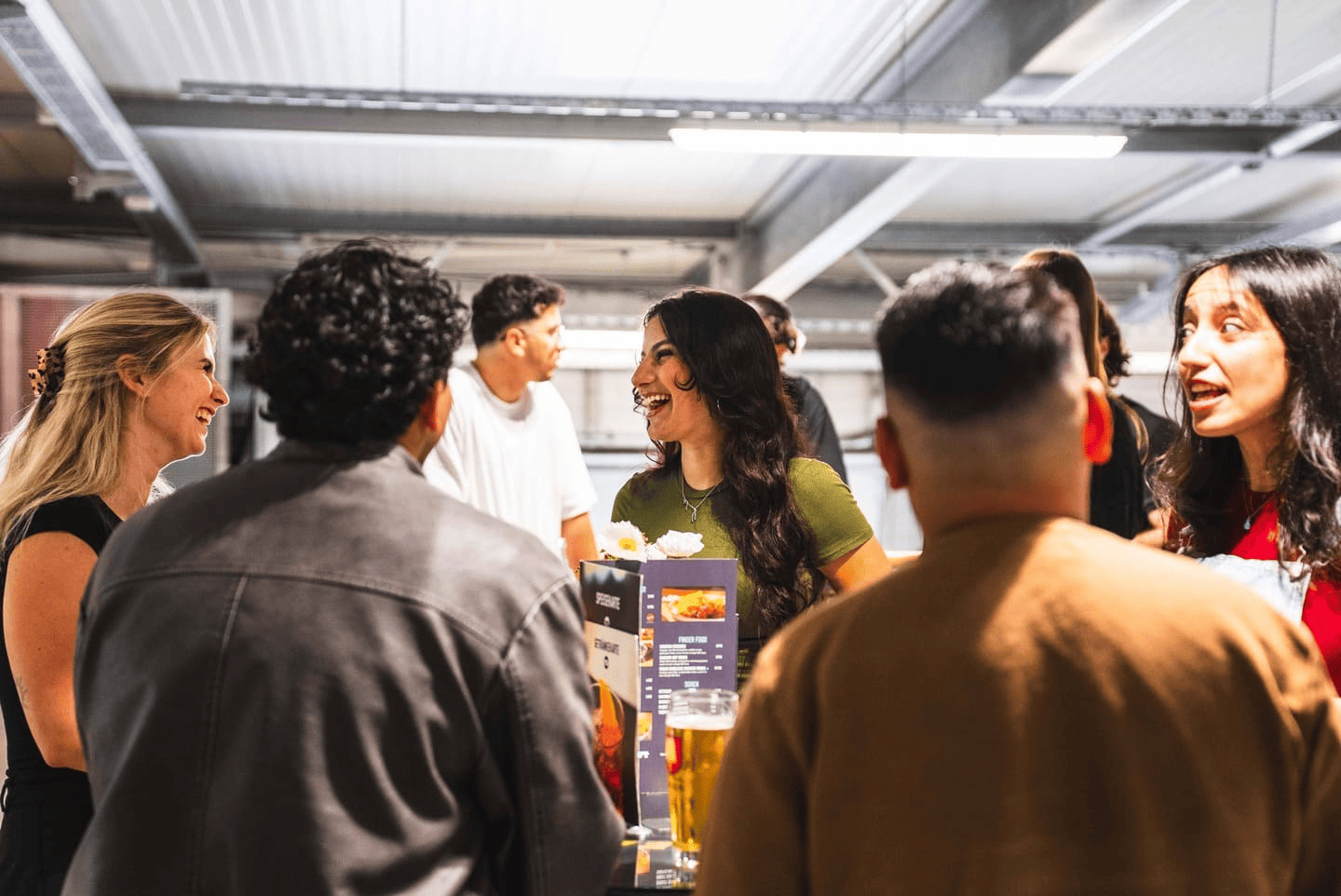 Eine Gruppe steht auf der Aussichtsplattform an den Tischen und unterhält sich.