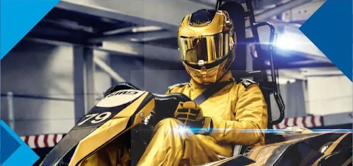 Ein Rennfahrer in einem goldenen Rennanzug mit Helm sitzt im Go Kart