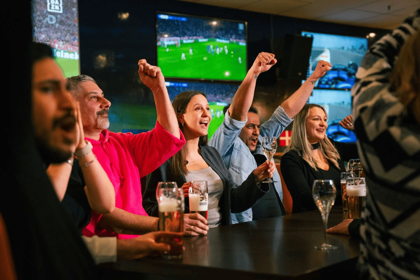 Menschen fiebern bei einem Fußballspiel in der Sportsbar mit.