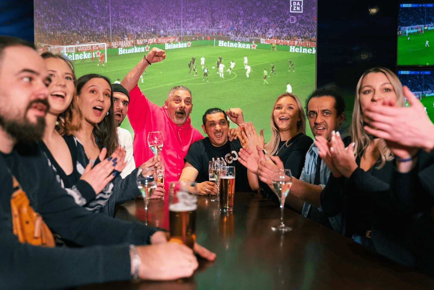 Menschen fiebern bei einem Fußballspiel in der Sportsbar mit.
