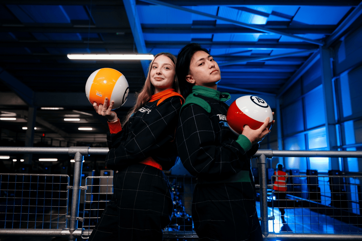 Two people in race suits holding bowling balls