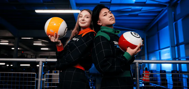 Two people in race suits holding bowling balls