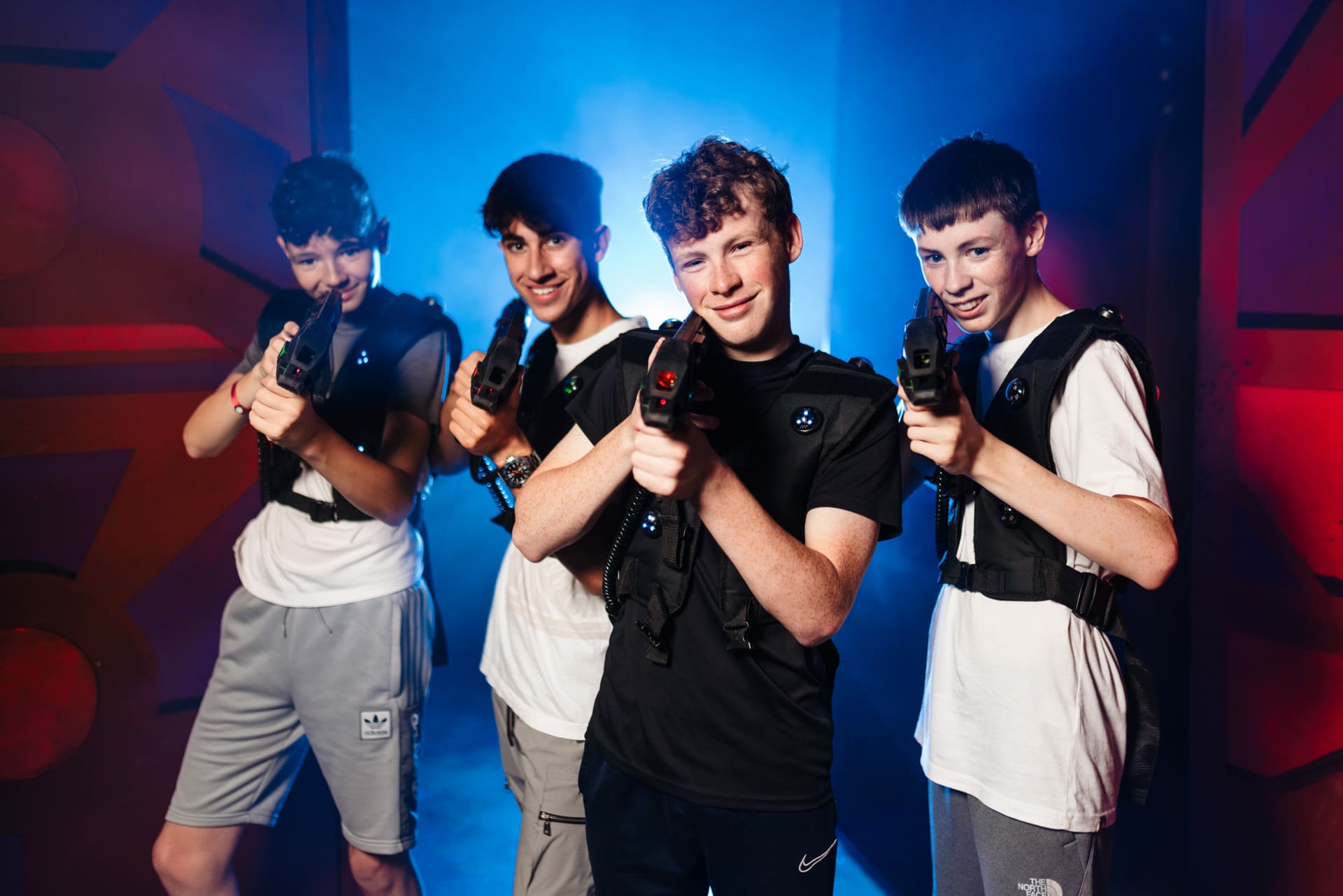 Boys playing indoor laser tag in a neon‑lit arena