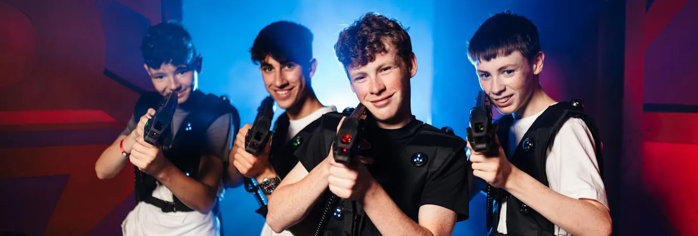 Boys playing indoor laser tag in a neon‑lit arena
