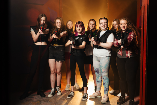 Kids completing a laser tag mission inside a neon arena