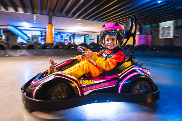 Mini racer aged 4–7 driving a go kart and smiling on the track