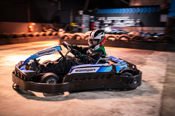 Child racing a junior go kart on an indoor track