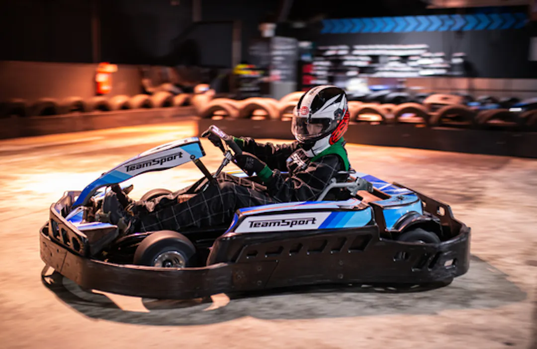 Child racing a junior go kart on an indoor track