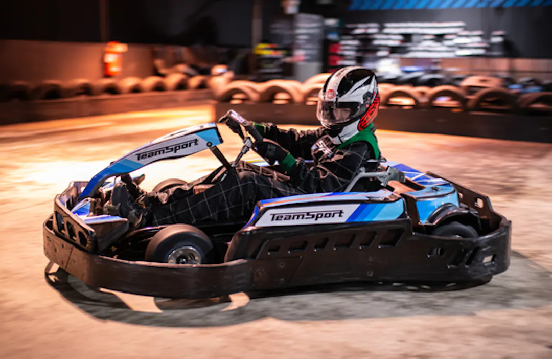 Child racing a junior go kart on an indoor track