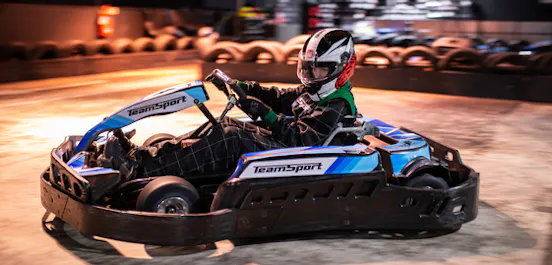 Child racing a junior go kart on an indoor track