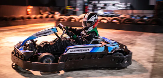 Child racing a junior go kart on an indoor track